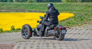 Moto 3 roues dans un champs de fleurs jaunes.