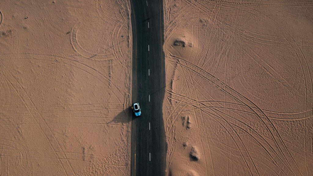 Les marques de pneu. Une voiture sur la route entourée par le désert.