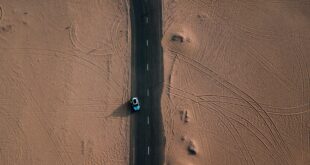 Les marques de pneu. Une voiture sur la route entourée par le désert.