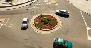 Des voitures circulent autour d'un rond-point.